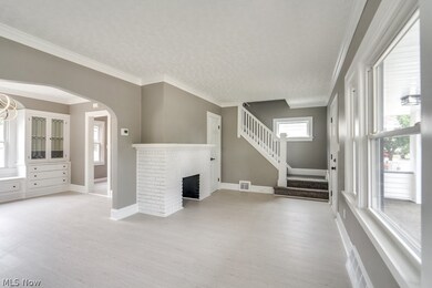 Unfurnished living room with light wood-type flooring, a brick fireplace, and ornamental molding