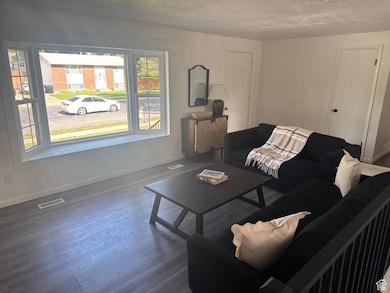 Living area featuring a textured ceiling, baseboards, and wood finished floors