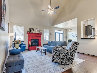 Living area featuring high vaulted ceiling, wood finished floors, a fireplace, and ceiling fan