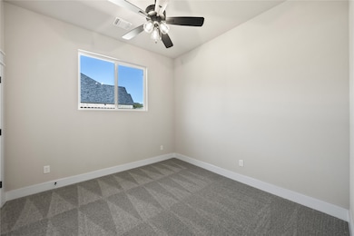 Carpeted empty room featuring baseboards and a ceiling fan