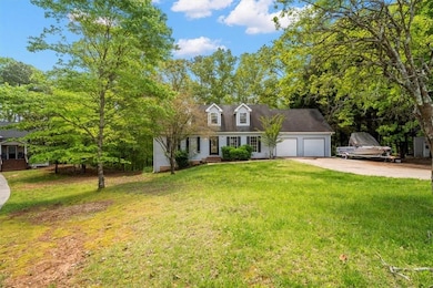 Cape cod home featuring a garage, driveway, and a front lawn