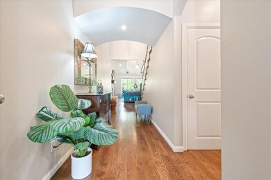 Hallway with wood-type flooring and vaulted ceilin