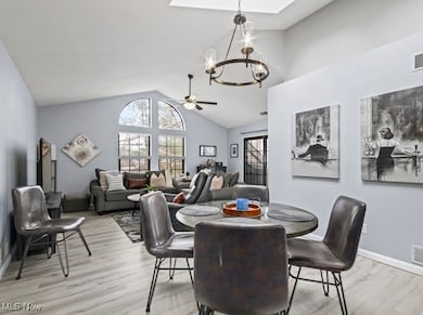 Dining space with a chandelier, light wood-type flooring, healthy amount of natural light, and high vaulted ceiling
