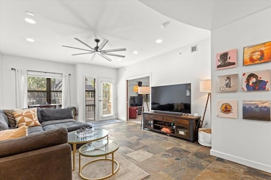 Living room with baseboards, visible vents, stone tile flooring, and recessed lighting