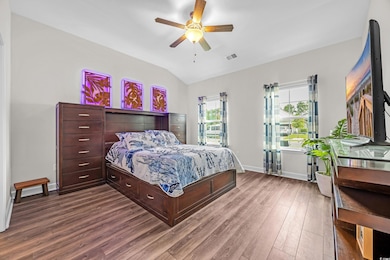 1st Primary Bedroom featuring dark wood-style flooring, vaulted ceiling, baseboards, and a ceiling fan