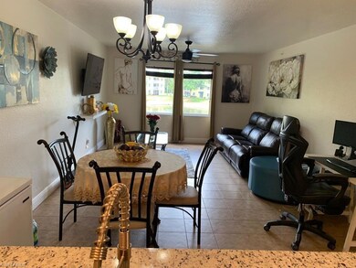 Dining space featuring a textured wall, light tile patterned flooring, a chandelier, a ceiling fan, and a textured ceiling