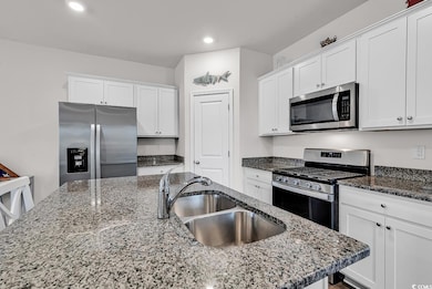 Kitchen featuring white cabinetry, a sink, and app