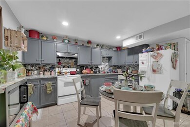 Kitchen with gray cabinets, tasteful backsplash, white appliances, and light tile floors