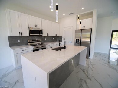 Kitchen with appliances with stainless steel finishes, white cabinets, light marble finish flooring, tasteful backsplash, and light stone counters
