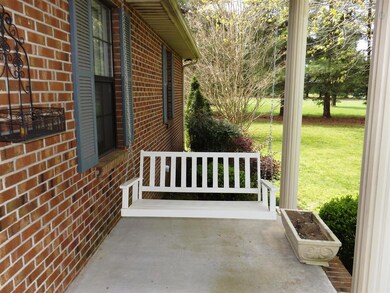 The sidewalk leads to the covered front porch that overlooks the front yard with mature trees. 