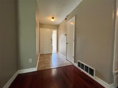 Corridor with a textured ceiling and light hardwoo