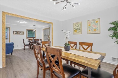 Dining area featuring a chandelier, light wood finished floors, baseboards, and a textured ceiling