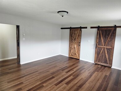 Empty room featuring baseboards, a barn door, a t
