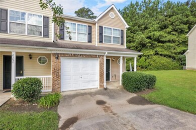 Traditional home with a porch, a garage, a front yard, driveway, and brick siding