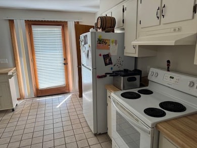 Kitchen with white electric range, under cabinet range hood, plenty of natural light, and light countertops