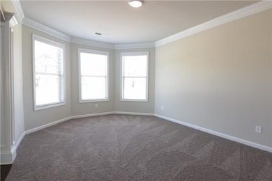 Empty room with dark colored carpet, visible vents