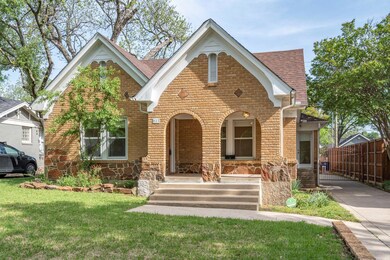 Tudor home with a front yard, fence, brick siding,