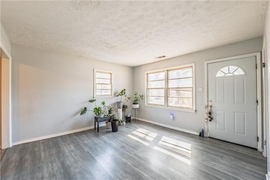 Foyer with visible vents, wood finished floors, baseboards, and a textured ceiling