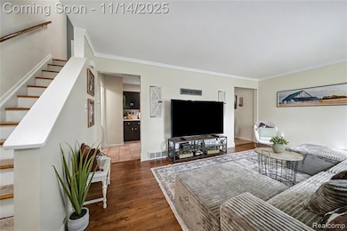 Living area featuring crown molding, dark wood finished floors, and stairs