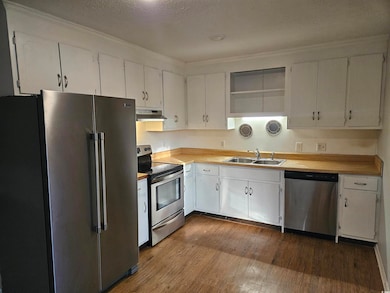 Kitchen with stainless steel appliances, a textured ceiling, open shelves, dark wood finished floors, and white cabinets