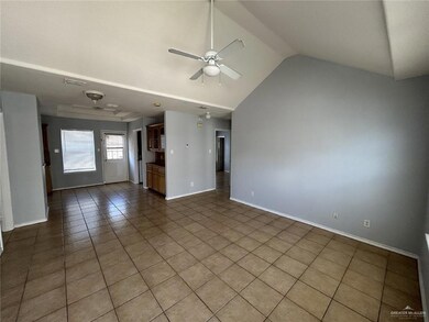 Unfurnished living room featuring tile patterned floors, ceiling fan, and vaulted ceiling