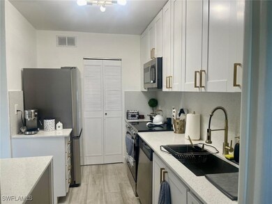 Kitchen with visible vents, light stone countertops, stainless steel appliances, white cabinetry, and a sink
