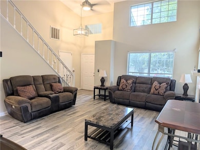 Living area with a towering ceiling, stairs, wood finished floors, and a ceiling fan