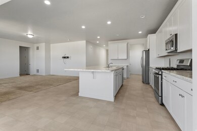 Kitchen featuring stainless steel appliances, recessed lighting, a breakfast bar, an island with sink, and white cabinets