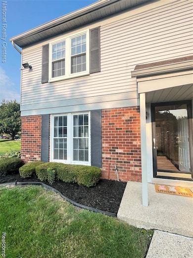 Doorway to property featuring brick siding and a yard