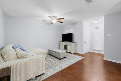 Living room with ceiling fan, concrete floors, and