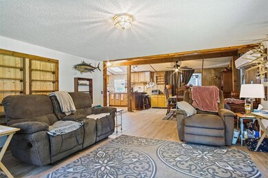 Living room featuring light wood-style floors, a textured ceiling, and wood walls