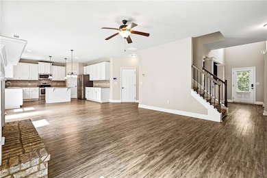 Unfurnished living room with ceiling fan, dark wood finished floors, stairs, and recessed lighting