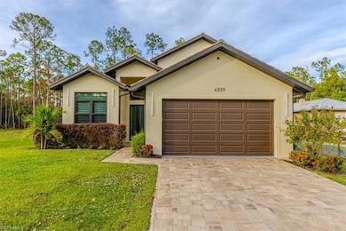 View of front of house with stucco siding, decorative driveway, a front lawn, and an attached garage