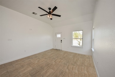 Features a high ceiling, durable tile flooring, a modern ceiling fan, and ample natural light from multiple windows.