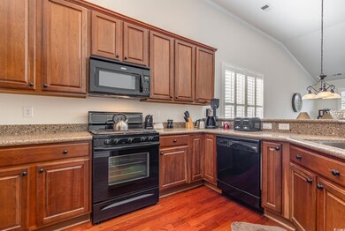 Kitchen with black appliances, wood-type flooring,