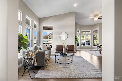 Living room with wood finished floors, high vaulted ceiling, and a ceiling fan