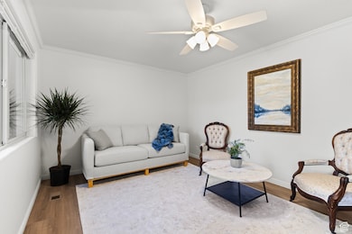 Living area featuring ornamental molding, wood finished floors, and ceiling fan