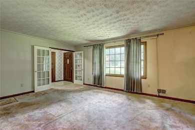 Carpeted empty room featuring french doors and a textured ceiling