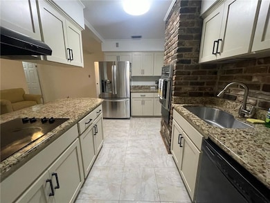 Kitchen with black appliances, a sink, and stone counters