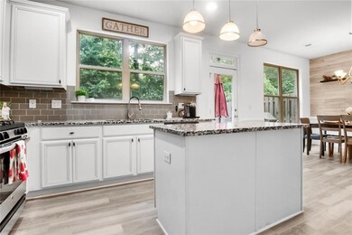 Kitchen with stainless steel range oven, dark stone counters, white cabinetry, light wood finished floors, and a center island