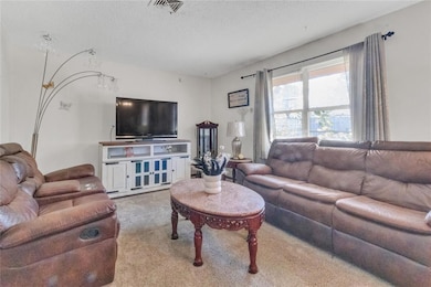 Living room with a textured ceiling and carpet flooring