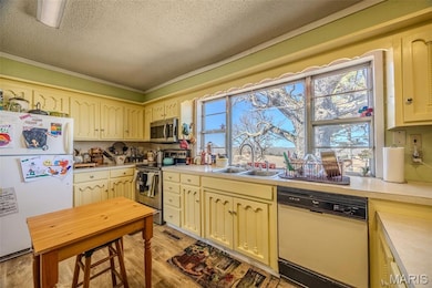 Kitchen featuring stainless steel appliances, light countertops, light wood finished floors, and a textured ceiling