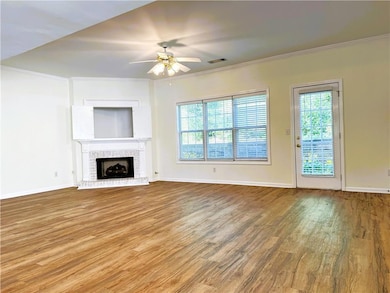Unfurnished living room with ornamental molding, wood finished floors, a fireplace, and a ceiling fan