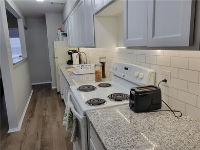 Kitchen with white appliances, dark wood-style flo