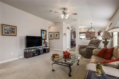 Living room featuring a ceiling fan, a chandelier, light colored carpet, and lofted ceiling