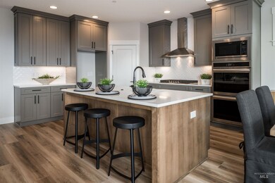 Kitchen with wall chimney exhaust hood, stainless steel appliances, backsplash, recessed lighting, and light countertops