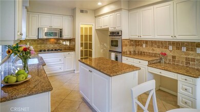 Plenty of storage in the nice white cabinetry, granite counters with travertine backsplash, large pantry and stainless steel appliances.