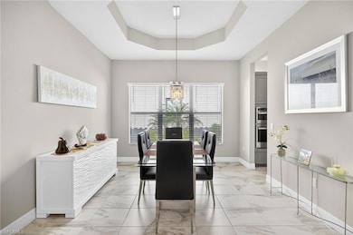 Dining area featuring light marble finish floors, a raised ceiling, and a chandelier