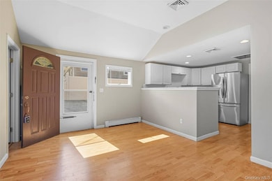 Entrance foyer featuring light wood-type flooring, lofted ceiling, baseboard heating, and recessed lighting