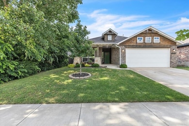 Craftsman-style home featuring concrete driveway, brick siding, an attached garage, and a front lawn